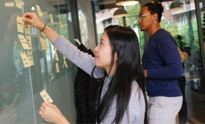 Photo of two people scenario planning with post-it-notes on a transparent board