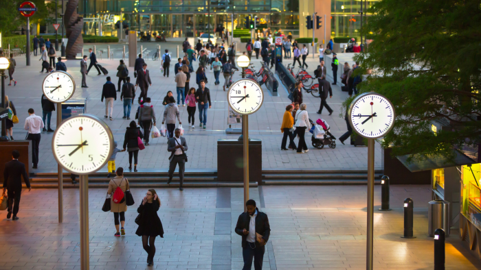 Canary Wharf in london by night, showing the iconic clocks and underground in the main plaza