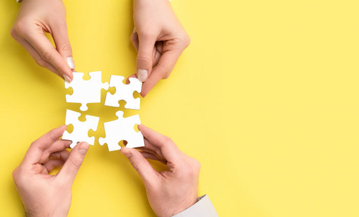 Two peoples hands hold together parts of a puzzle