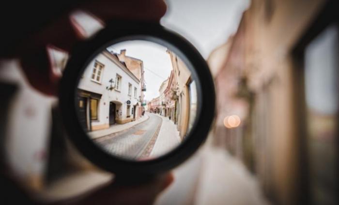 Someone holding a camera lens to zoom in on a street